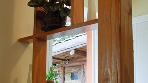 A wooden shelf with plants, a white chair, and a window reflecting an outdoor scene.