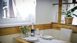 A dining table set for two with plates, a bottle of champagne, and a glass.