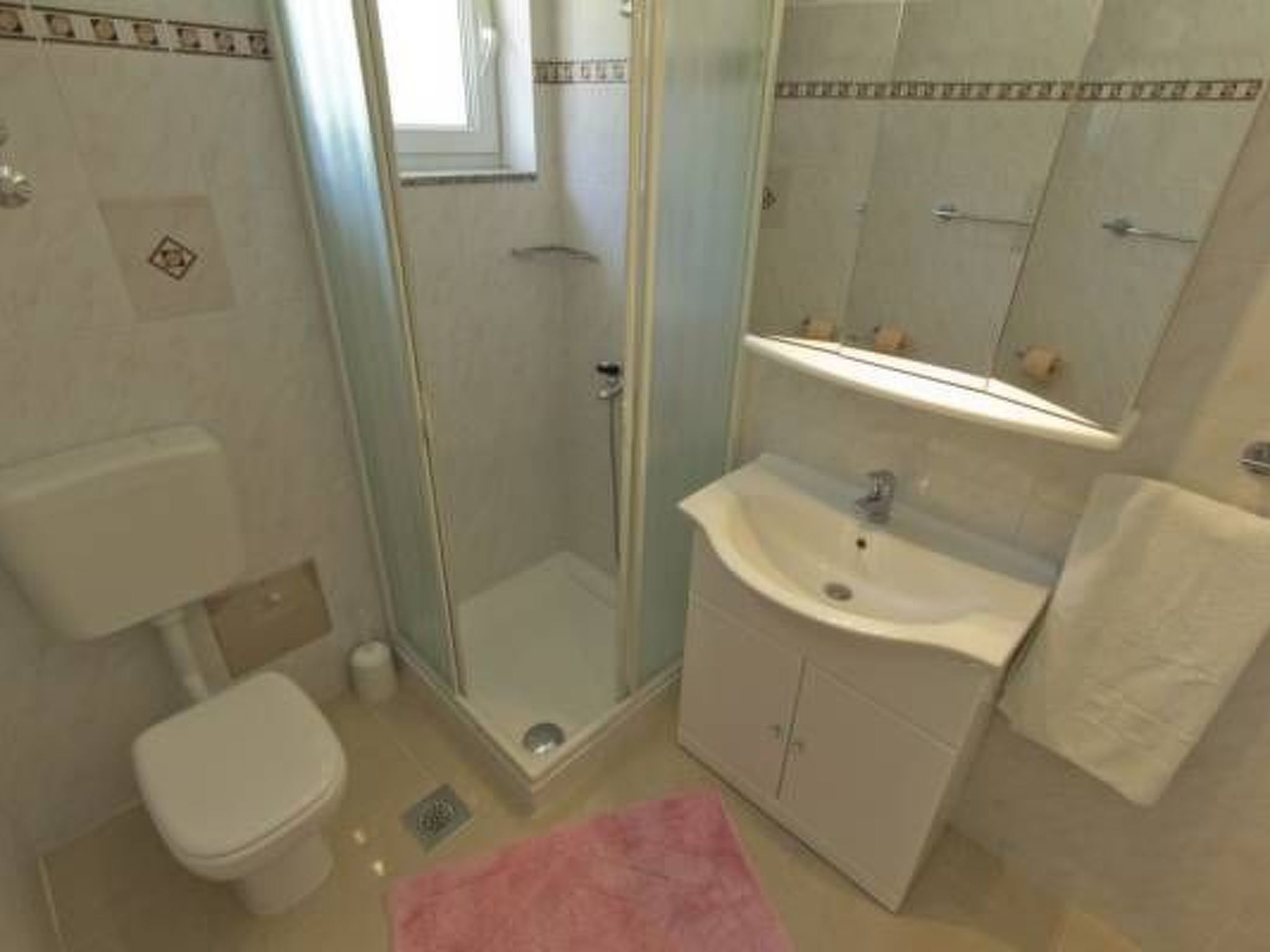 Un baño con inodoro, cabina de ducha de vidrio, lavamanos y espejo.