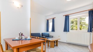 Et værelse med et træspisebord, stole, et lille bord og blå gardiner.