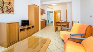 En moderne stue med et tv-skab i træ, en sofa og et spisebord med stole.