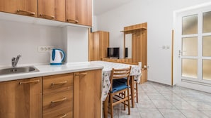 Una cocina compacta con armarios de madera, un lavamanos y un comedor con mesa y sillas.