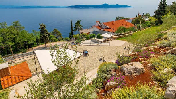 Una propiedad costera con un patio, vistas al mar y un jardín con diversas plantas.