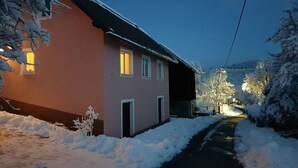 Ett snötäckt bostadsområde med ett hus som har en röd fasad och flera fönster.