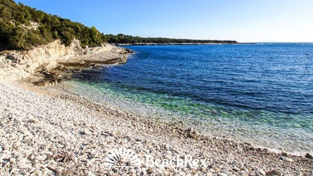 Ein Kiesstrand mit klarem Wasser und einer felsigen Küste.