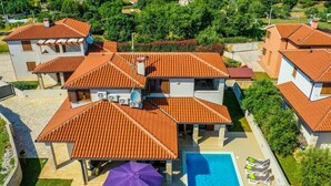 Ein Wohnkomplex mit mehreren Gebäuden, einem Schwimmbad und einer überdachten Terrasse.
