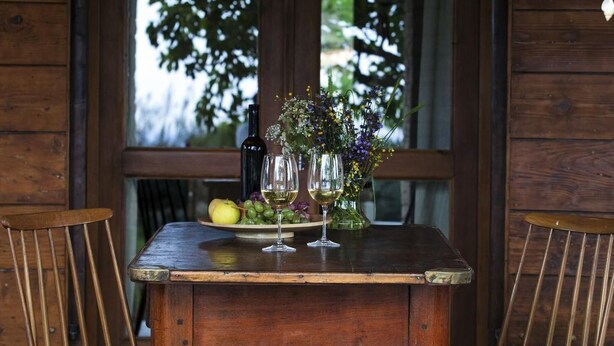 Una mesa de madera con dos sillas, un jarrón con flores y una botella sobre la mesa.