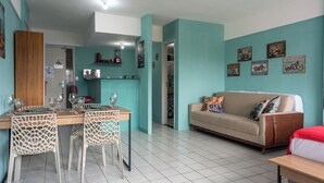 A dining area with a table set for four, chairs with a unique lattice design, a sofa with colorful cushions, and wall-mounted motorcycle-themed decorations. - Recife Center (Recife)
