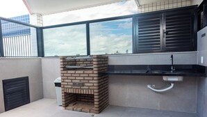 An outdoor kitchen area with a brick oven, a sink, and a window overlooking a cityscape. - Recife Center (Recife)
