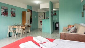 A hotel room with a bed, a dining table with chairs, a kitchenette, and a living area with a sofa. - Recife Center (Recife)