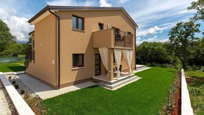 A two-story house with a balcony, a small garden, and a clear sky. - Modernes Apartment mit Balkon und Gemeinschaftsgarten am Waldrand by Interhome (Dracevac)