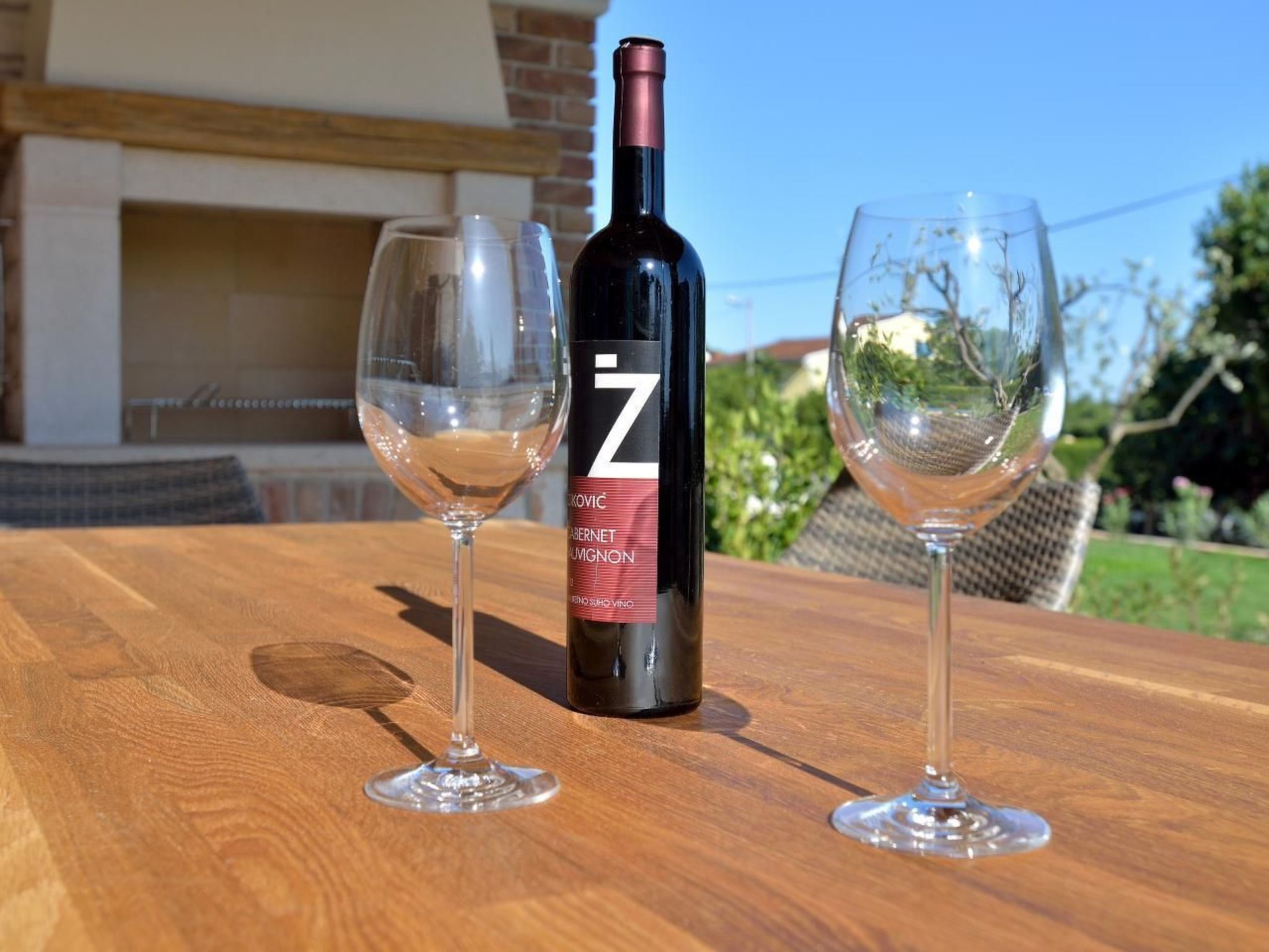 A bottle of wine and two glasses on a wooden table.