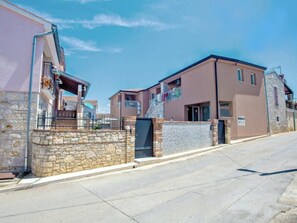 Eine Wohnstraße mit Häusern, die Steinmauern und Balkone haben.