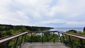 A wooden deck with a metal railing overlooking a coastal landscape with trees and a body of water. - Apartment Noemi2 by Interhome (Poreč/Tar)