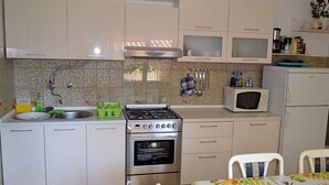 A compact kitchen with a gas stove, oven, microwave, and a small refrigerator. - Wohnung "Sonja Dajla" direkt am Strand by Interhome (Buzinija)