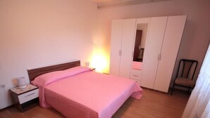 A bedroom with a bed, nightstand, wardrobe, and chair. - Wohnung "Sonja Dajla" direkt am Strand by Interhome (Buzinija)