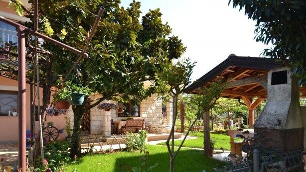 A garden with a stone bench, a pergola, and a brick oven. - Wohnung "Sonja Dajla" direkt am Strand by Interhome (Buzinija)