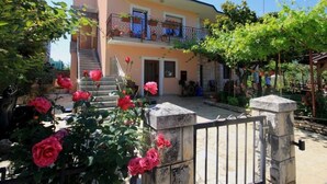 A two-story building with a balcony, surrounded by lush greenery and blooming flowers. - Wohnung "Sonja Dajla" direkt am Strand by Interhome (Buzinija)