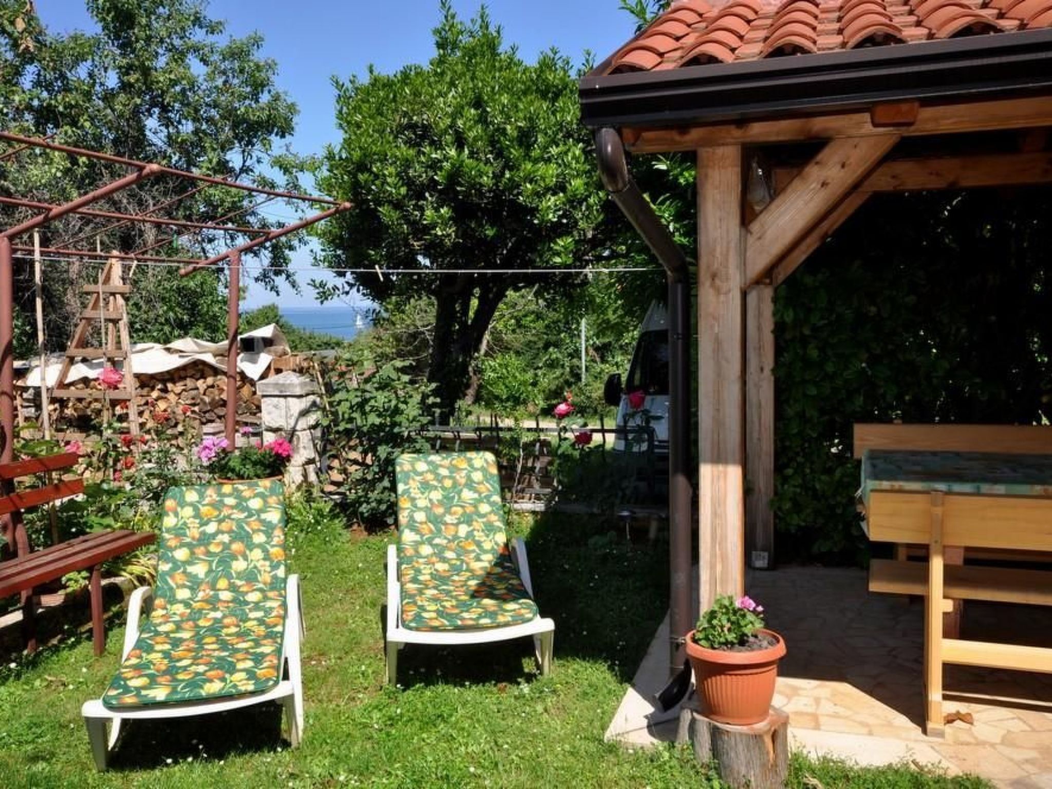 Two lounge chairs with a floral pattern, a wooden pergola, and a bench.