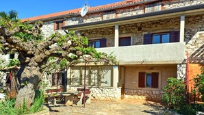 A stone building with a courtyard, featuring a pergola with climbing plants.