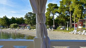 A beachside view with a pool, lounge chairs, and a pavilion. - in Murine mit Großer Terrasse by Interhome (Umag/Murine)