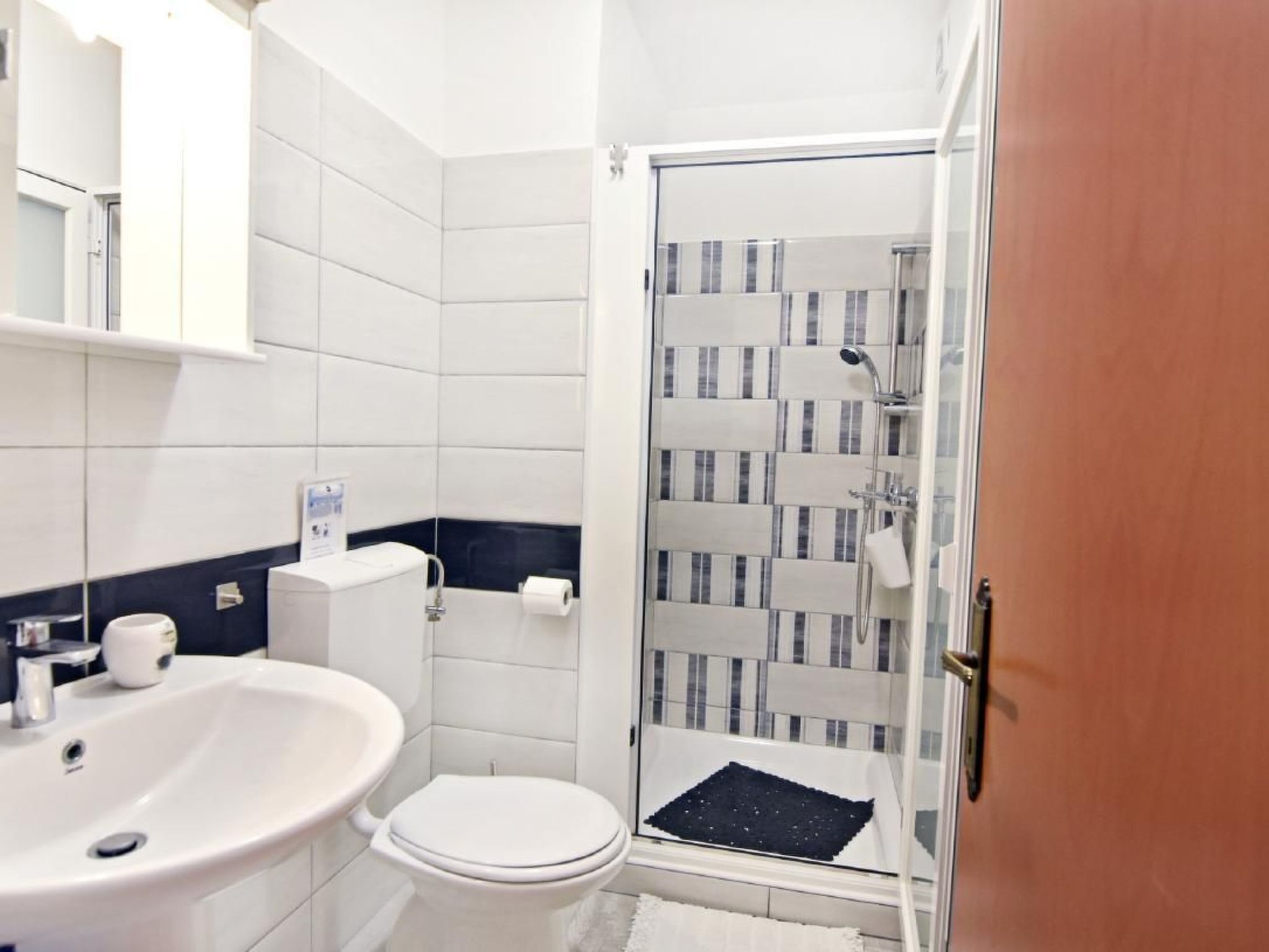 A modern bathroom with a white sink, toilet, and shower.