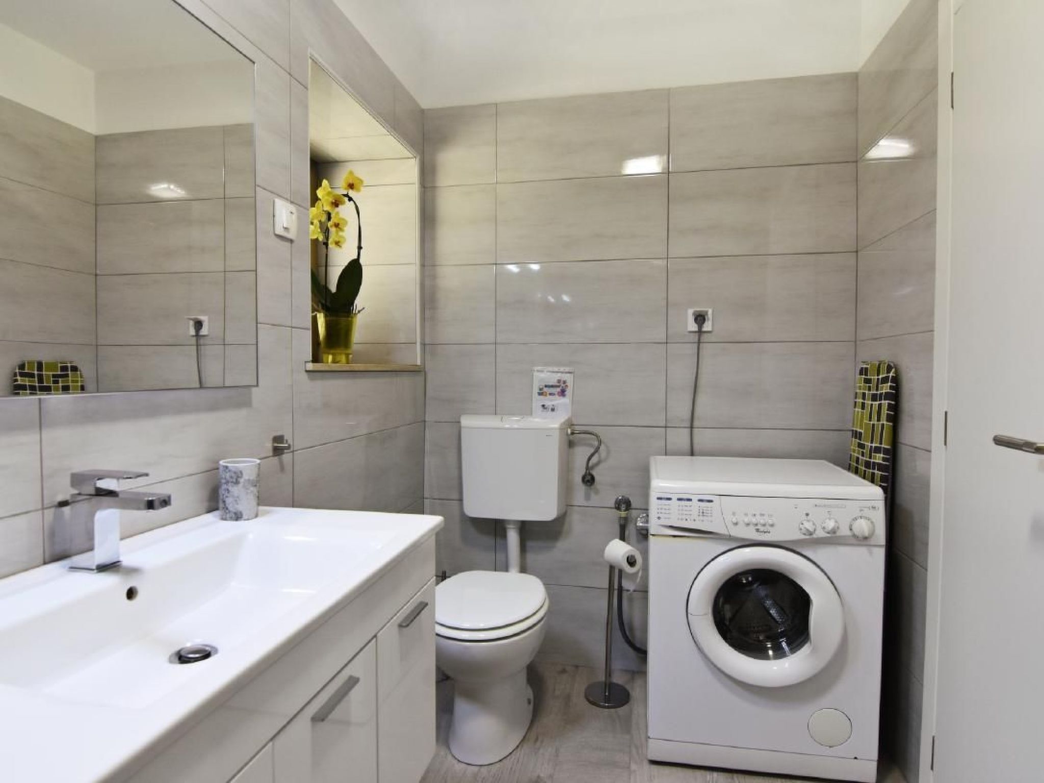Ein modernes Badezimmer mit Waschbecken, Toilette und Waschmaschine.