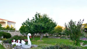 Ein Garten mit Steinmauer, Baum und einer weißen Schwan-Skulptur.