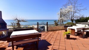 An outdoor patio with a view of the sea, a barbecue grill, and a table with a white tablecloth. - Appartement in Zambratija mit Schöner Terrasse by Interhome (Umag/Zambratija)