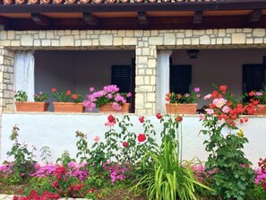 Ein Gebäude mit Steinmauern und zahlreichen Fenstern, jedes mit Blumenkästen, die rosa und rote Blumen beherbergen.