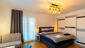 Una habitación de hotel moderna con una cama grande, un sofá, una mesita y una silla.