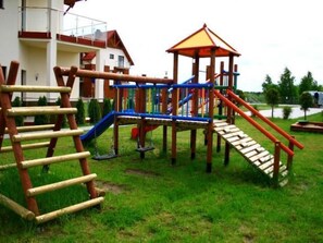A playground with a wooden slide, climbing net, and a small shelter. - für 6 Personen by Interhome (Jastrzebia Gora)