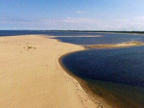 Un paysage côtier avec une plage de sable et une étendue d’eau en forme de courbe.