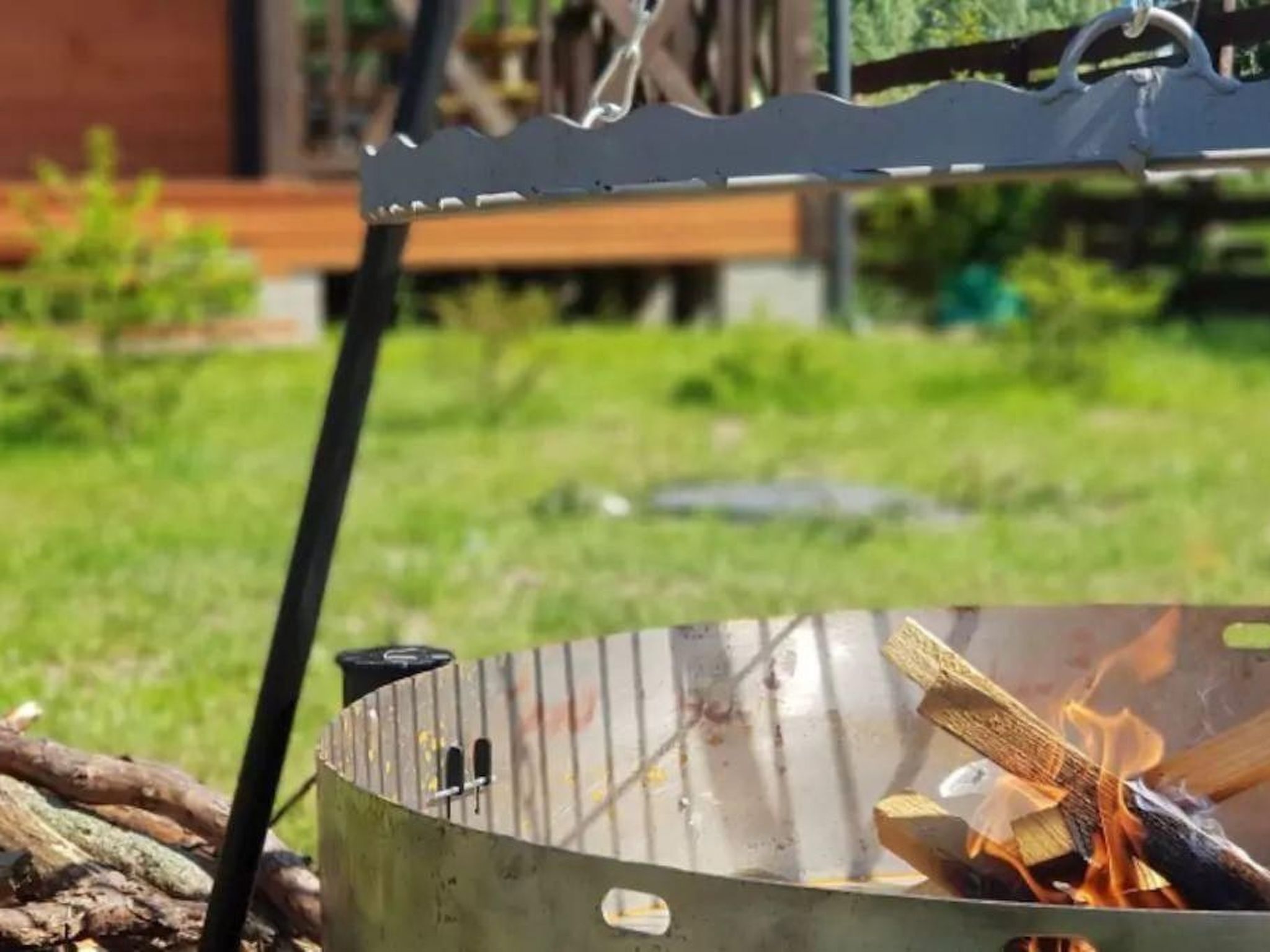 Un gril en métal dans lequel brûle un feu, entouré de bûches.