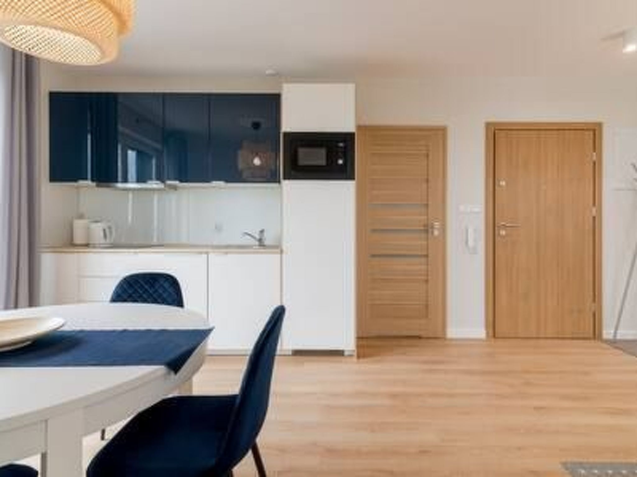 A modern kitchen with dark blue cabinets, a white countertop, and a wooden door.