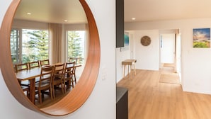 A modern interior with a round mirror, a dining area with wooden furniture, and a hallway leading to another room.