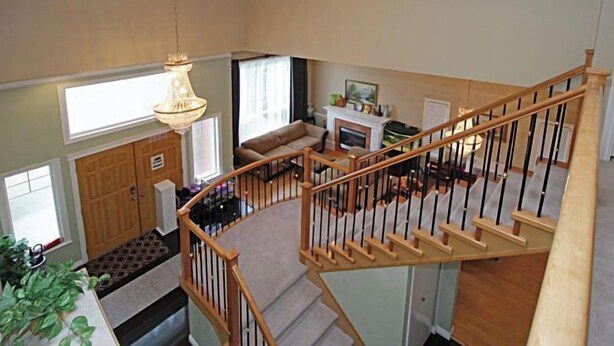 A spacious living area with a staircase, a fireplace, and a large window. - aa misu (Richmond)