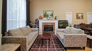 A living room with two patterned sofas, a fireplace, and a dining area with a table and chairs. - aa misu (Richmond)