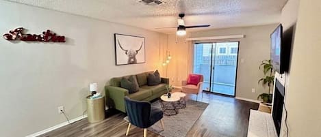 A modern living room with a green sofa, a round coffee table, and a ceiling fan.