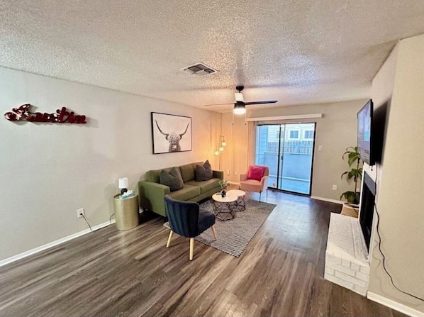 A modern living room with a green sofa, a round coffee table, and a ceiling fan.