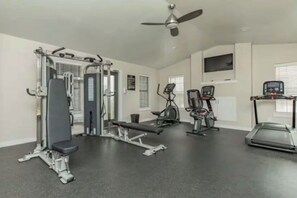 A gym with various exercise equipment including a bench press, elliptical machines, and a treadmill.