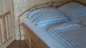 Une petite pièce en bois, avec un lit simple et une porte.