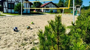 Un terrain de beach-volley avec un filet, entouré de sable et de verdure.