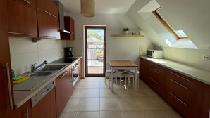 Une cuisine moderne avec des meubles en bois, un lave-vaisselle Bosch, un évier et une petite table à manger avec des tabourets.