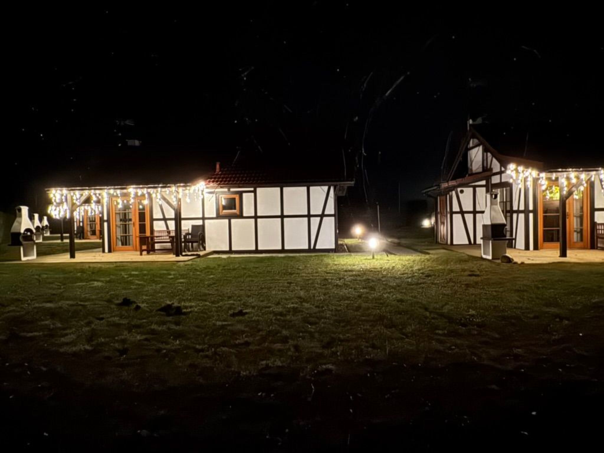 Ein Haus mit überdachter Terrasse, einer kleinen Holzterrasse und einem Rasen.