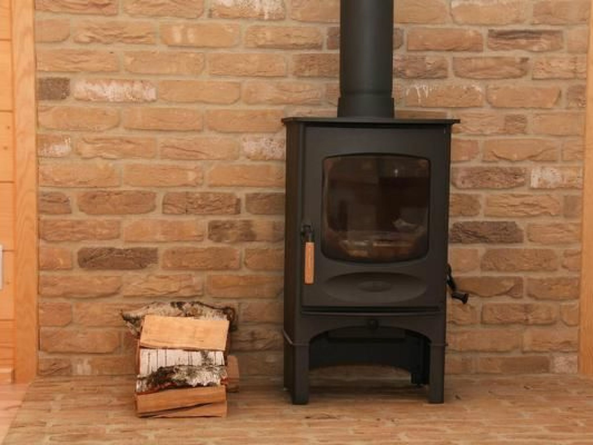 A stone wall interior with a black wood-burning stove.