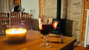 A cozy room with a wooden table, a lit candle, a glass of red wine, and a wood-burning stove. - "Dom4" mit Wasserblick by Interhome (Sarbinowo)