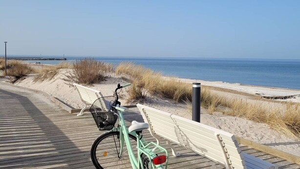 A wooden boardwalk leading to a beach with a bicycle parked on it. - Beach Club-Häuser direkt am Strand by Interhome (Dziwnówek)
