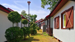 A row of white buildings with red roofs and wooden shutters, connected by a narrow pathway.