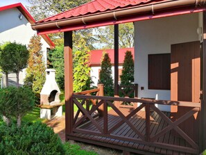 A wooden deck with a red roof, a stone bench, and a wooden door. - Beach Club-Häuser direkt am Strand by Interhome (Dziwnówek)